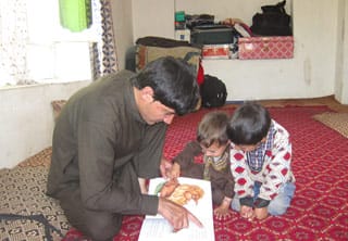 adult reading to 2 young Afghan boys