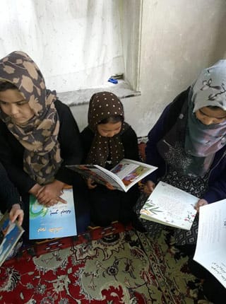 3 Afghan children with Hoopoe books seated on the floor