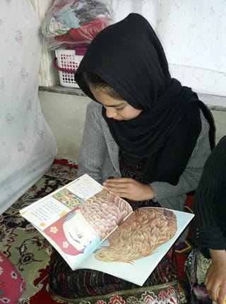 Young Afghan girl reading The Old Woman and the Eagle
