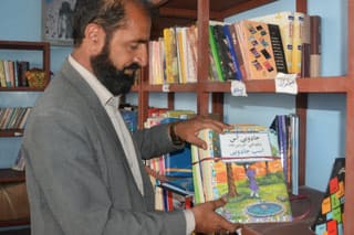 Teacher at Ghulam Mohammad Ghobar high school shows new package of Dari-Pashto Hoopoe books