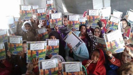 Afghan girls holding up copies of The Magic Horse