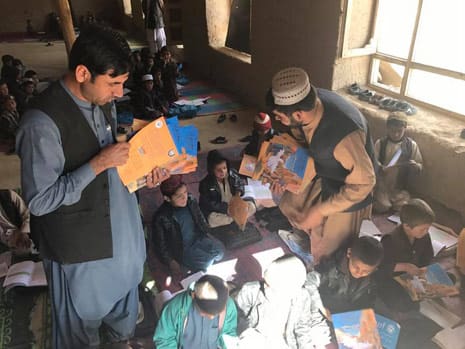 passing out copies of The Silly Chicken to Afghan kids in the classroom