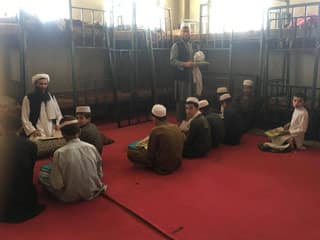 Afghan boys in a classroom with Nuristani-Pashto editions of The Lion Who Saw Himself in the Water