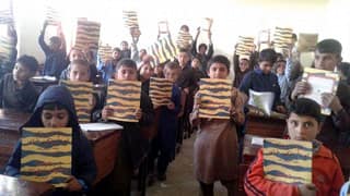 Afghan boys in the classroom with copies of The Clever Boy and the Terrible, Dangerous Animal