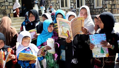 Afghan girls with a variety of Hoopoe books standing outside a school.