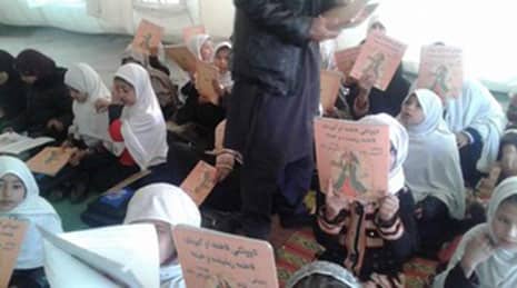 Teacher handing out Hoopoe books in a classroom in Afghanistan