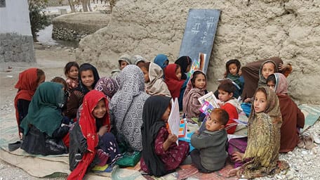 Girls in an outdoor classroom with Hoopoe Books in Chaparhar district in Nangarhar province
