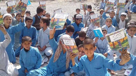 Boys in Afghanistan holding up copies of the book The Magic Horse