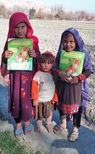 3 Afghan children with Hoopoe books in winder landscape