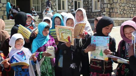 girls holding Hoopoe Books delivered by Saber Husseini