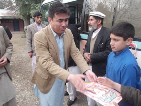 The Public Library Director hands out Hoopoe Books to students in Jalalabad.