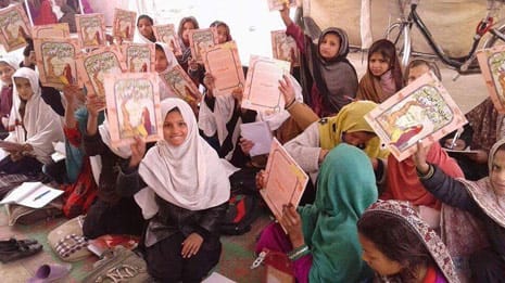 Afghan Girls holding up copies of the book The Old Woman and the Eagle