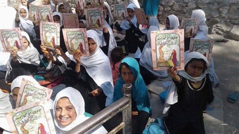 Girls in Afghanistan holding up copies of The Old Woman and the Eagle