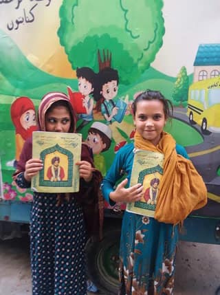 3 young Afghan girls holding copies of The Wisdom of Ahmad Shah (Dari-Pashto edition)