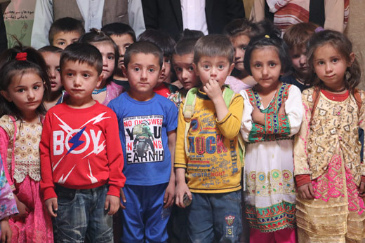 Shughni kids wearing colorful clothes with their teachers in the background
