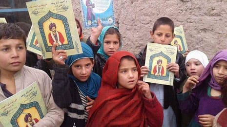 Boys and girls in Afghanistan holding up copies of The Wisdom of Ahmad Shah