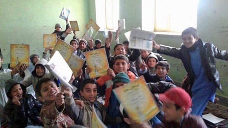 Boys in an Afghan classroom enthusiastically holding up Hoopoe books