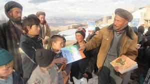 Men passing out Hoopoe books to children in Afghanistan