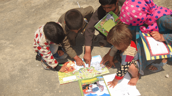 Afghan kids gathered around a Hoopoe book.