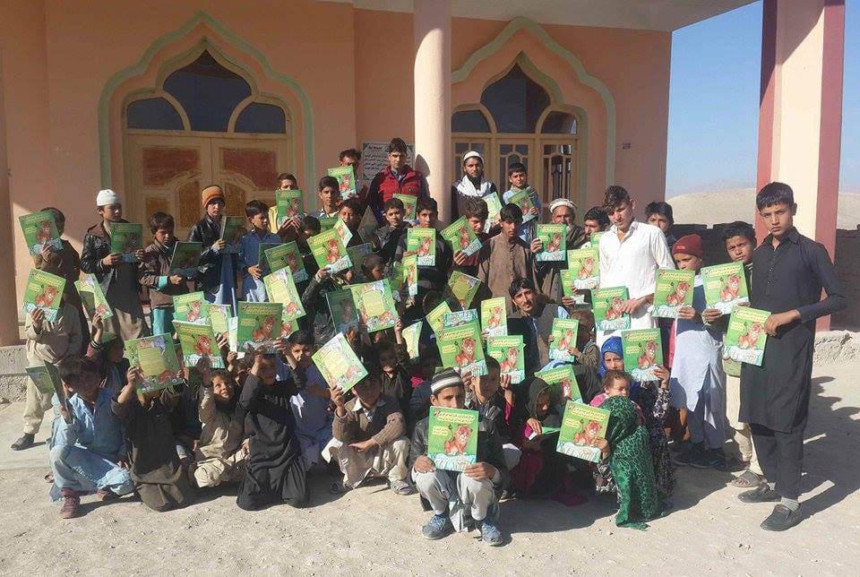Group of Afghan kids holding up copies of the Sawji-Pashto edition of The Lion Who Saw Himself in the Water
