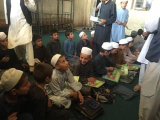 Afghan boys in a classroom receiving Nuristani-Pashto editions of The Lion Who Saw Himself in the Water