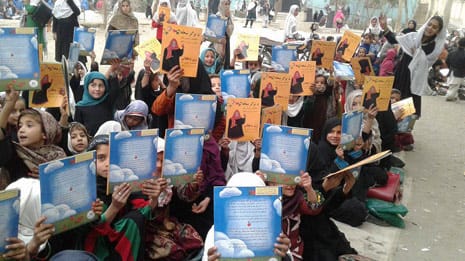 Afghan girls holding up Hoopoe books (The Farmer's Wife)