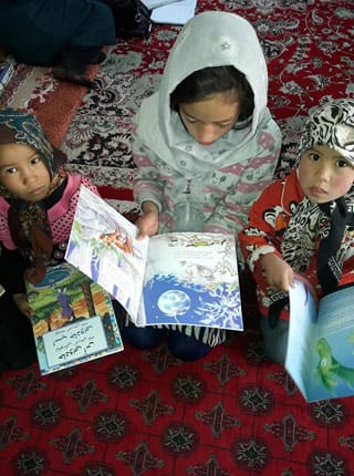 3 Afghan children with Hoopoe books seated on the floor
