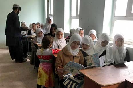 Afghan girls in a classroom with the book The Stranger's Farewell