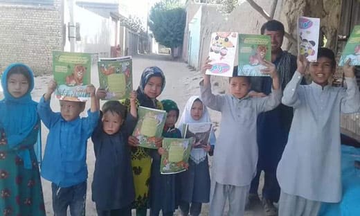Afghan children holding copies of The Lion Who Saw Himself in the Water