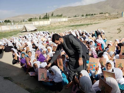 Wesa distributing the book Fatima the Spinner and the Tent to Afghan children