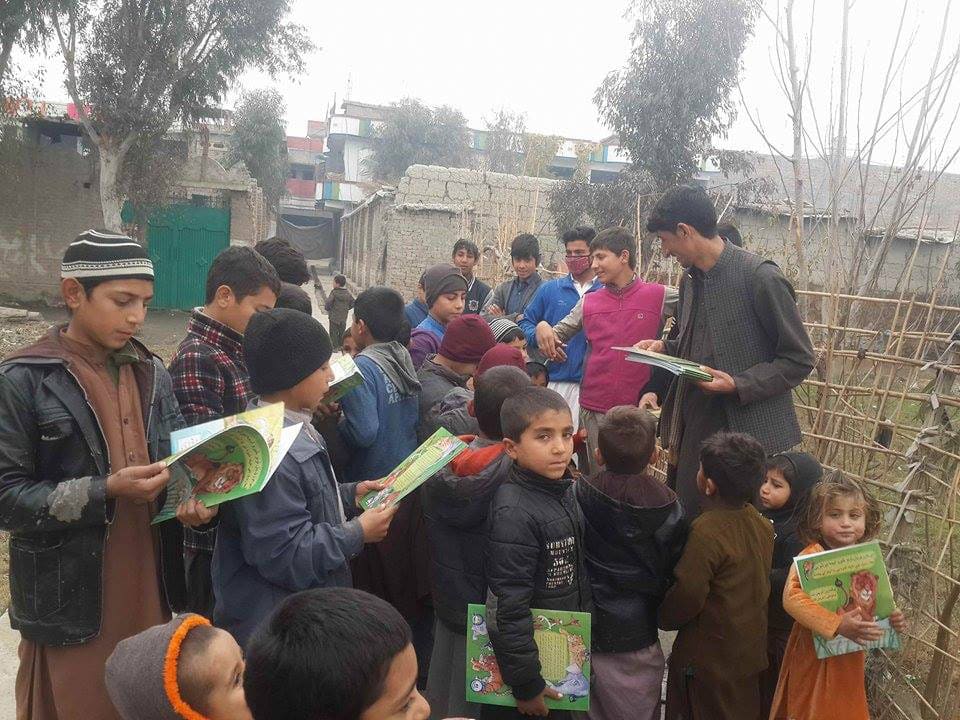 Afghan kids crowd around waiting to receive a copy of the Sawji-Pashto edition of The Lion Who Saw Himself in the Water
